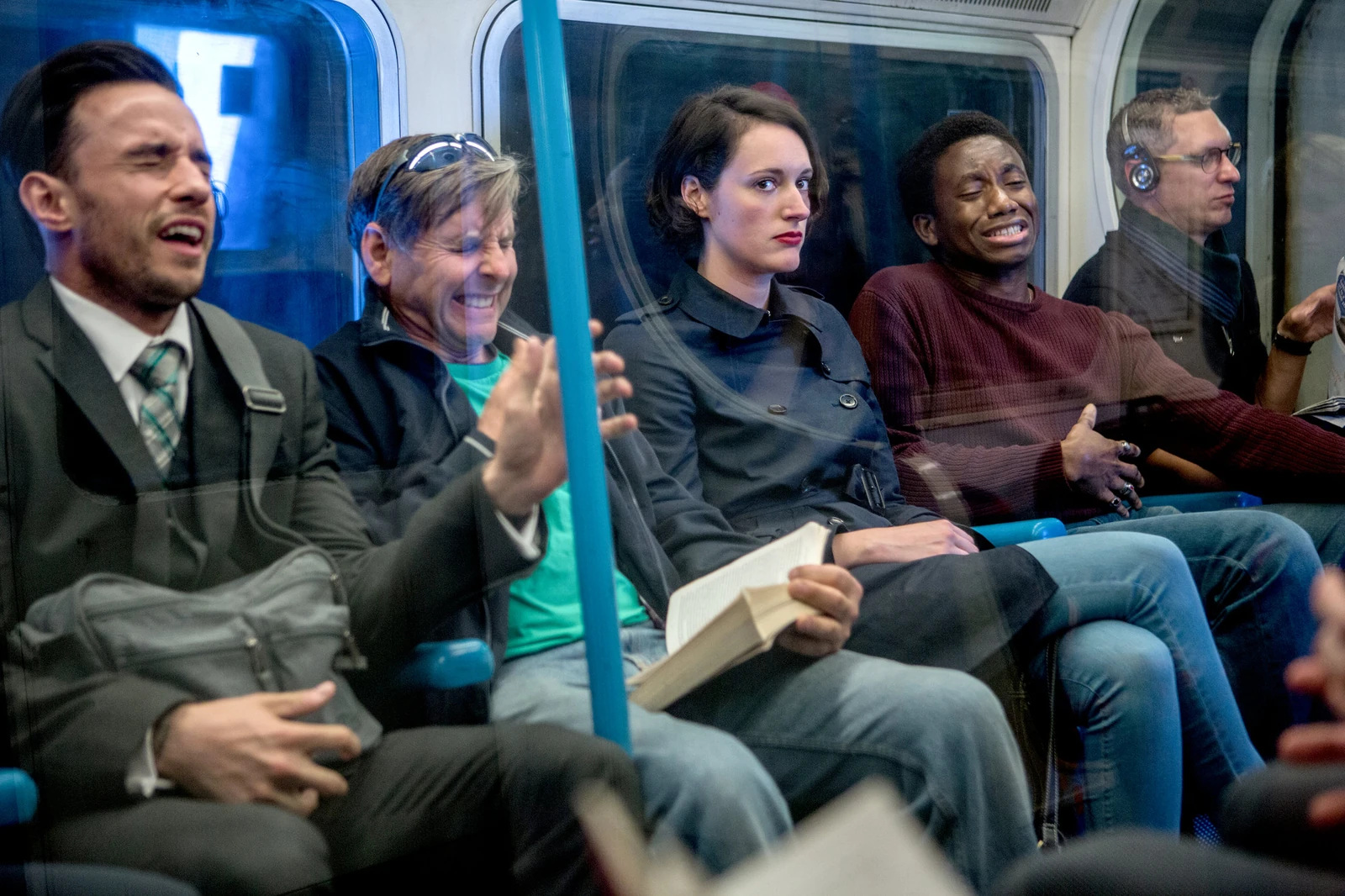 Original full photograph of five seated commuters reacting on the subway.